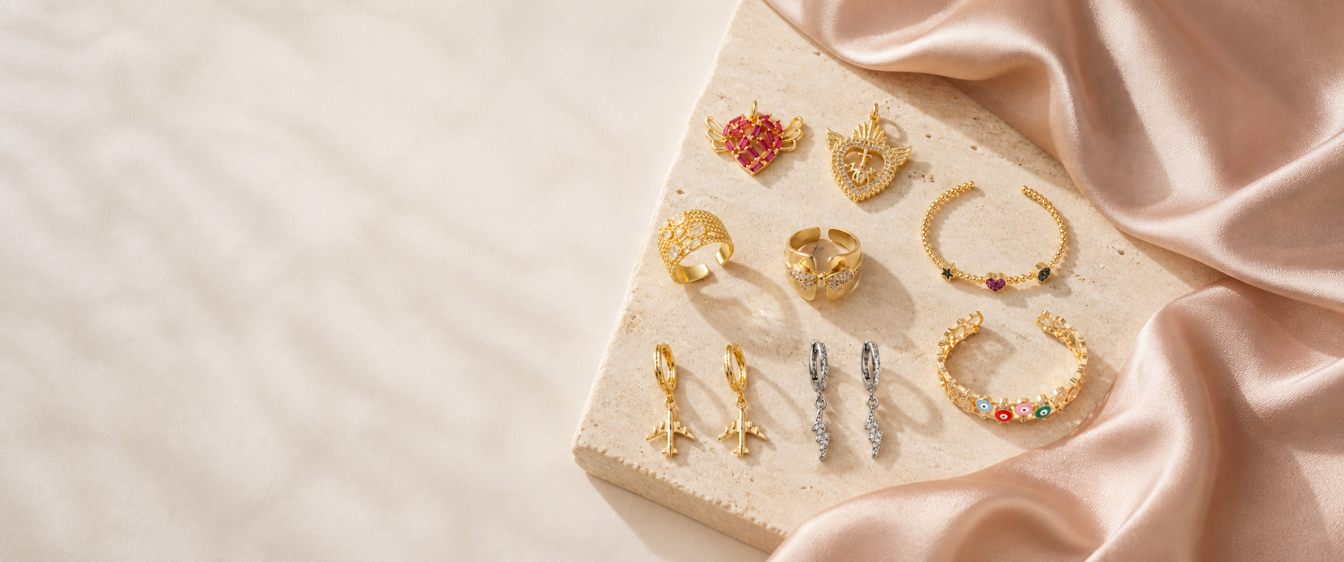 A selection of Kessia jewelry arranged on warm travertine and satin